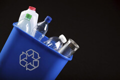 Image of recycling bin with various plastic containers poking out the top.