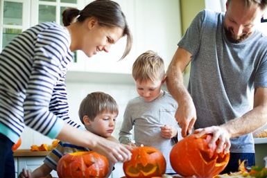 Image of young family carving pumpkins.