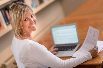Image of smiling woman paying bill online.